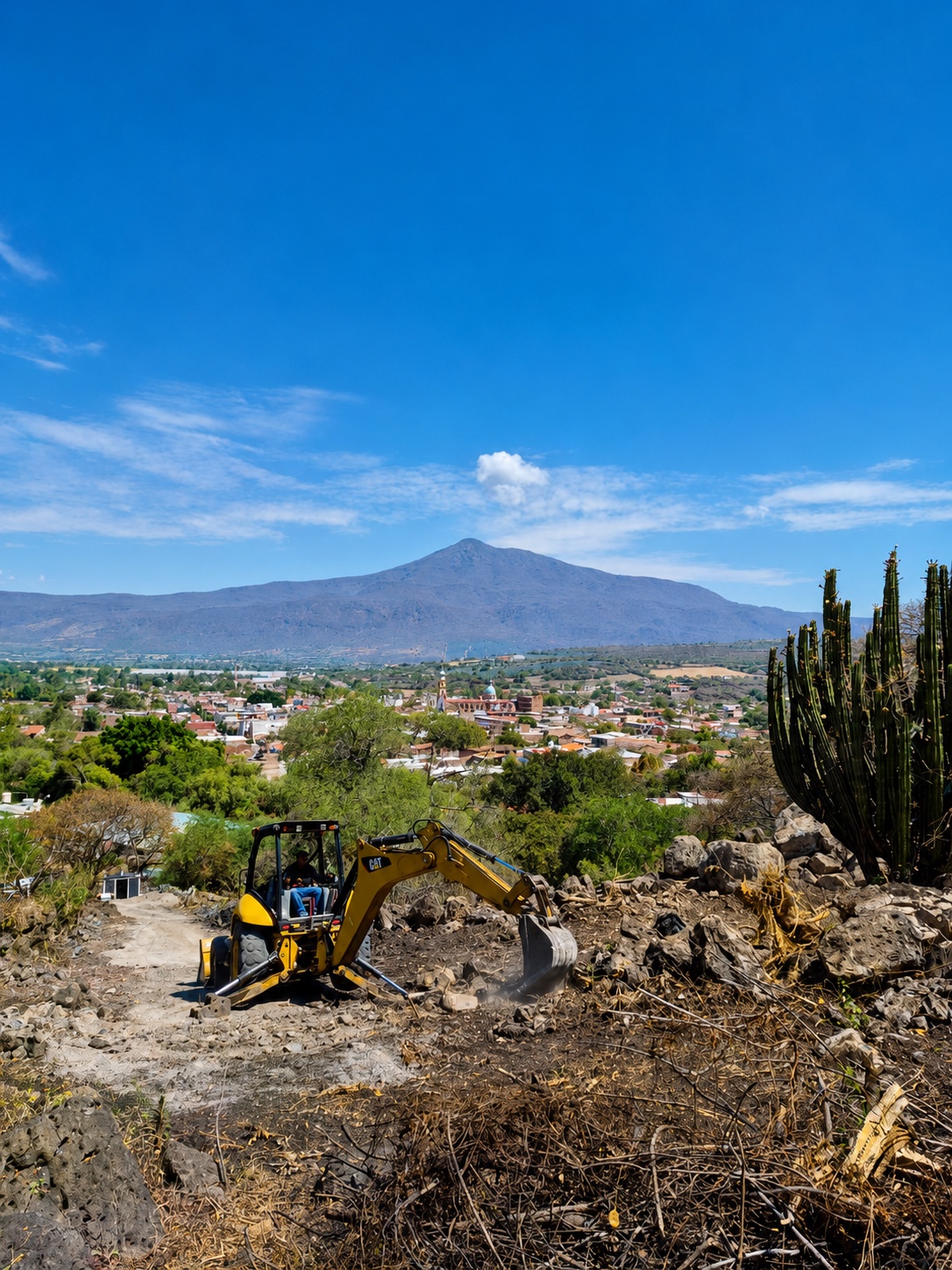 Excavadora despejando el terreno con vista a Teocuitatlán y al cerro al fondo.